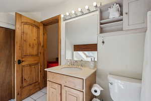 Bathroom with toilet, a skylight, tile patterned flooring, and vanity