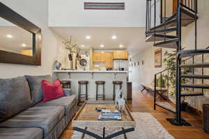 Living room featuring light wood-type flooring, baseboards, recessed lighting, and stairs