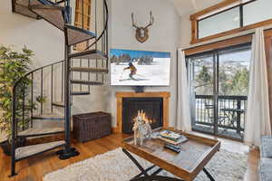 Living room featuring a lit fireplace, stairway, and light wood finished floors