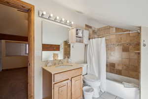 Full bath with visible vents, tile patterned flooring, vaulted ceiling, shower / bath combination with curtain, and vanity