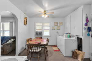 Dining space with a wealth of natural light, washing machine and dryer, ceiling fan, and arched walkways