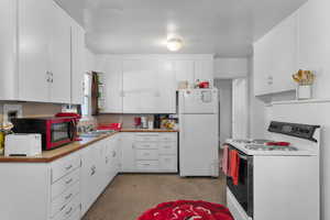 Kitchen featuring white appliances, white cabinets, and a sink