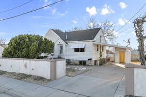 View of front of property featuring driveway, fence, and roof with shingles