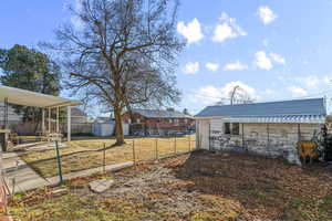 View of yard featuring a patio area, a fenced backyard, a storage shed, and an outbuilding