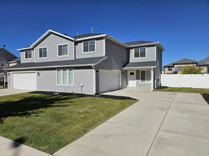 Traditional-style house featuring a garage, a front yard, fence, and driveway