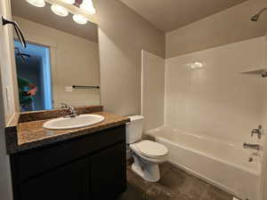 Bathroom with a textured ceiling, bathing tub / shower combination, vanity, and toilet