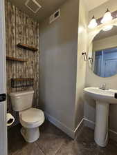 Half bath with toilet, visible vents, and baseboards