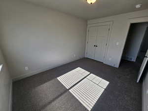 Unfurnished bedroom featuring a closet, a textured ceiling, and baseboards