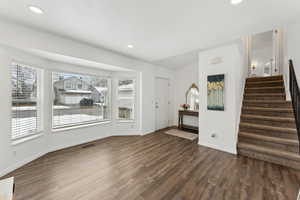 Interior space with dark wood-style floors, recessed lighting, visible vents, and stairs