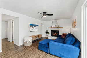 Living room featuring ceiling fan, a fireplace, wood finished floors, and baseboards