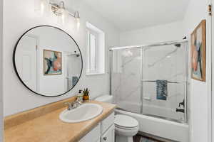 Full bathroom with toilet, enclosed tub / shower combo, and vanity