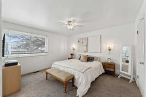 Bedroom featuring a ceiling fan, light colored carpet, visible vents, and baseboards