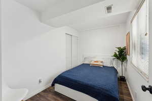 Bedroom featuring dark wood-style flooring, visible vents, and baseboards