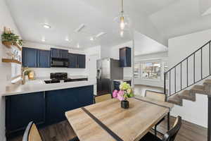 Dining space with dark wood-style floors, recessed lighting, and stairs