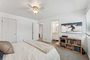 Bedroom featuring light carpet, ceiling fan, and ensuite bath