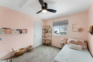 Bedroom with light carpet, ceiling fan, and baseboards