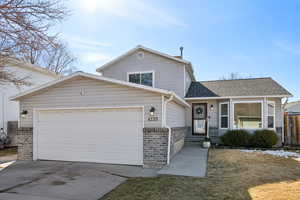 View of front of home with a shingled roof, concrete driveway, brick siding, and an attached garage