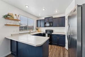 Kitchen featuring light countertops, a peninsula, and black appliances