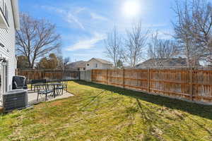 View of yard with a fenced backyard, central AC unit, and a patio