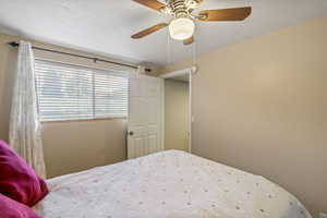 Bedroom with a textured ceiling and a ceiling fan