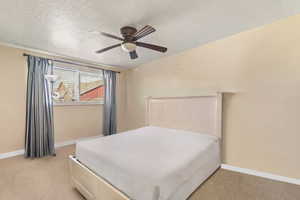 Bedroom with light carpet, a textured ceiling, and baseboards