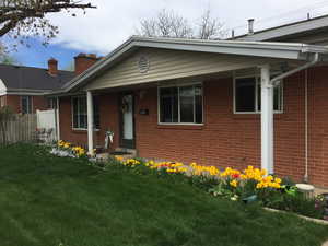 View of front of home featuring brick siding, fence, and a front lawn