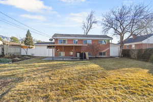 Back of house featuring brick siding, a patio, fence, and a lawn