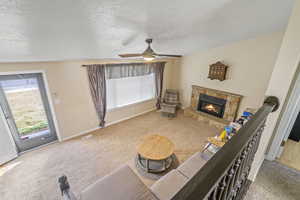 Living room featuring carpet floors, a fireplace, visible vents, and a textured ceiling