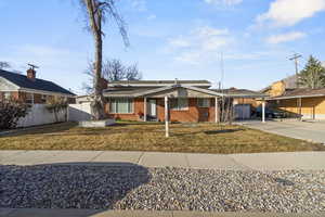 View of fronthttps://assets.utahrealestate.com/photos/280x210/hb4957364_8fe9bf9a5bb30665f67832d57dbc118a_67c0cd58644ea.jpg facade featuring a front yard, fence, a carport, and brick siding