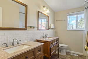 Bathroom featuring toilet, two vanities, a sink, and visible vents