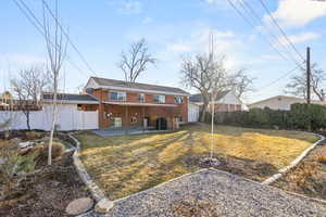 Rear view of house with a yard, a patio, brick siding, and fence