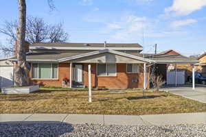 Bungalow with brick siding, driveway, roof with shingles, a carport, and a front yard