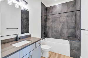 Bathroom featuring vanity, tub / shower combination, wood finished floors, and toilet