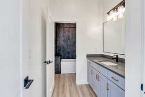 Full bathroom featuring a soaking tub, wood finished floors, and vanity