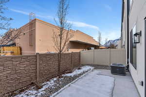 Snow covered patio featuring central AC, a fenced backyard, and a mountain view