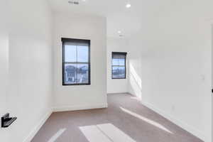 Empty room featuring recessed lighting, visible vents, baseboards, and light colored carpet