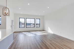 Unfurnished living room with baseboards, recessed lighting, a chandelier, and light wood-style floors