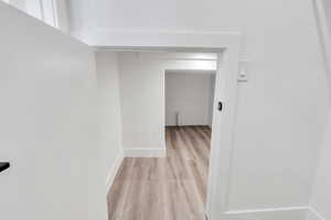 Corridor with light wood-style flooring and baseboards