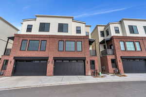 Townhome / multi-family property featuring driveway, a garage, board and batten siding, and brick siding