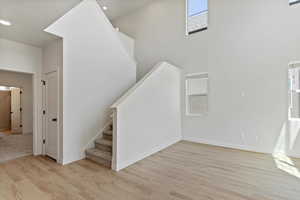 Staircase with wood finished floors, plenty of natural light, recessed lighting, and a towering ceiling