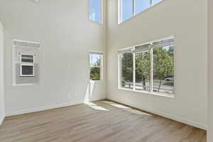 Spare room with wood finished floors and a towering ceiling