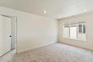 Spare room featuring light colored carpet, a textured ceiling, and recessed lighting