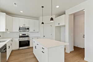 Kitchen with stainless steel appliances, tasteful backsplash, light wood-type flooring, recessed lighting, and white cabinets
