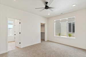 Unfurnished bedroom featuring light carpet, a walk in closet, recessed lighting, ceiling fan, and a closet