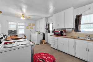 Kitchen with electric stove, light countertops, white cabinetry, a sink, and ceiling fan