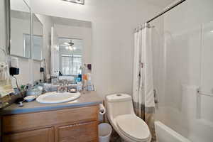 Bathroom featuring toilet, a ceiling fan, shower / tub combo with curtain, and vanity