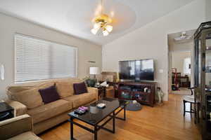 Living area featuring light wood-style floors, vaulted ceiling, and a ceiling fan