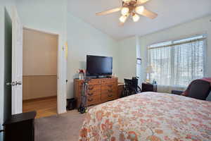 Carpeted bedroom with vaulted ceiling, baseboards, and ceiling fan