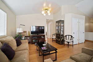 Living area featuring lofted ceiling, baseboards, ceiling fan, and light wood finished floors