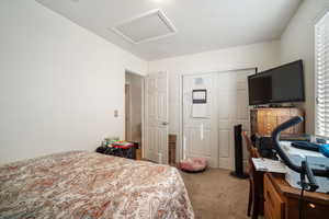 Bedroom featuring carpet, attic access, and a closet